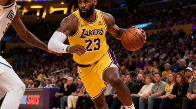 NBA常规赛湖人主场迎战勇士，詹姆斯突破上篮的精彩瞬间，背景为斯台普斯中心满座观众
